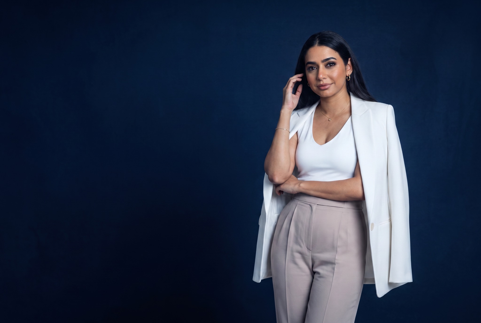 Amel Amamou, Tunisian entrepreneur and business builder, standing in a cream blazer and tan trousers.
